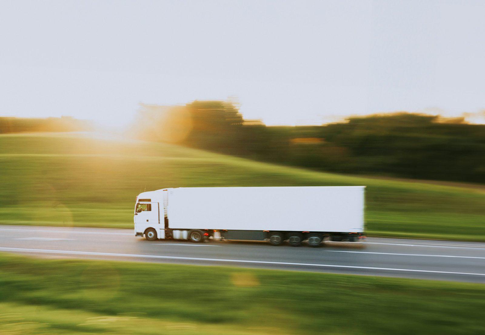 An articulated lorry on a motorway at sunset